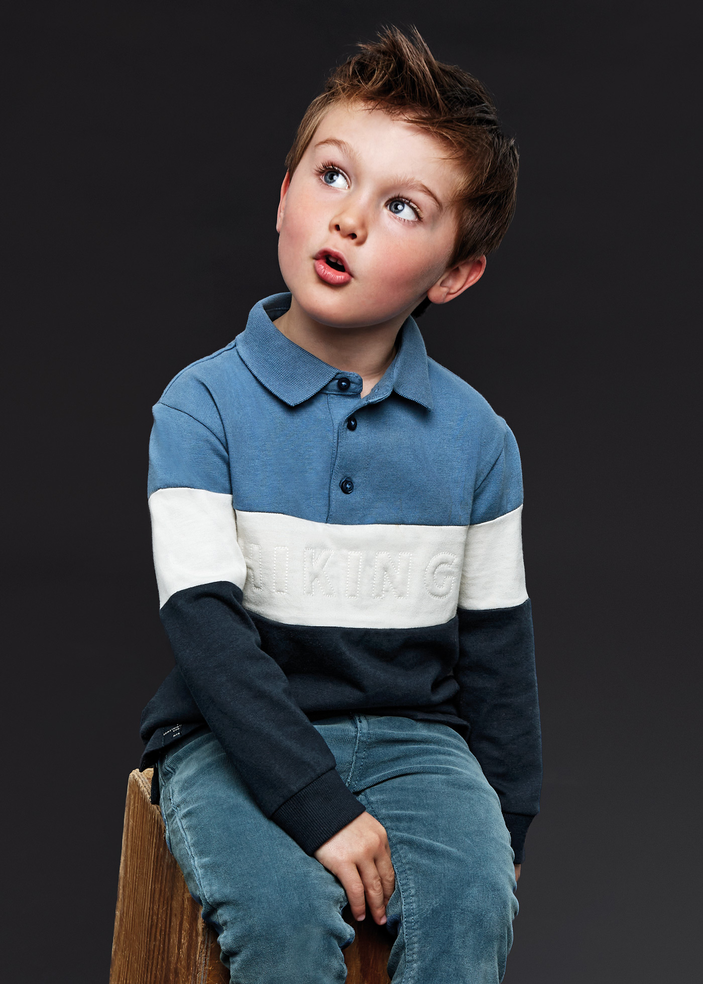 Boy in gray and black stripe polo shirt and blue denim jeans